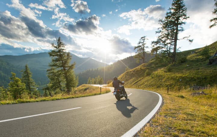 Motorcycle driver riding in Alpine highway, Nockalmstrasse, Austria, central Europe.